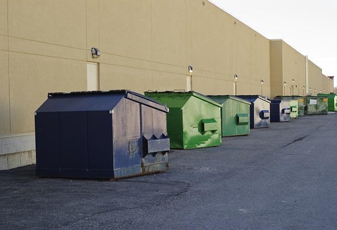 a waste management truck unloading into a construction dumpster in Modena